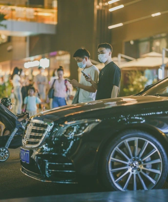 商场里 一名戴口罩的男子站在一辆汽车旁边