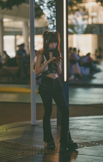 一名年轻女子靠在电线杆上 给另一个人看手机拍照