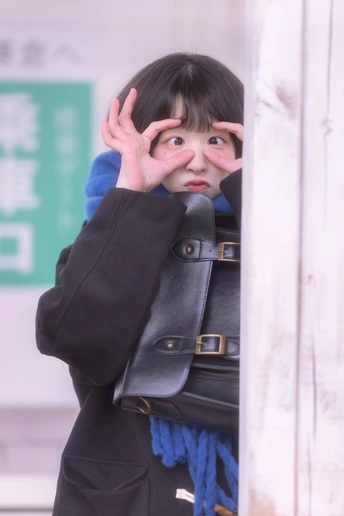 一位年轻女子举着黑色包包遮住脸部并遮住眼睛