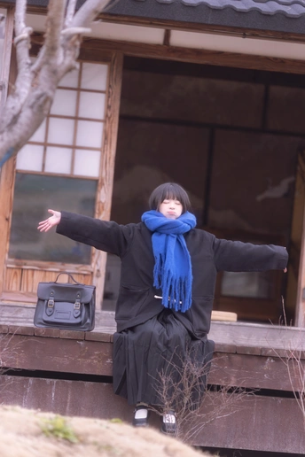 一个戴蓝围巾的年轻女子坐在房子的门廊上