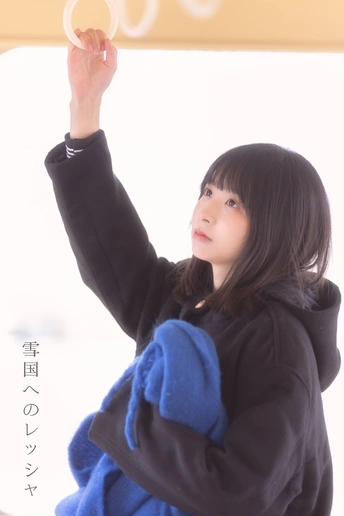 一位年轻女子站在窗前举起手来 手上戴着戒指。