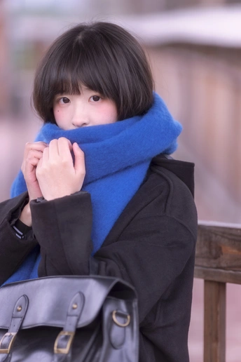 一位年轻女子戴着蓝色围巾 拿着黑色包