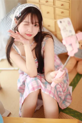 一个穿着粉红色裙子的年轻女孩坐在床边 旁边有一个泰迪熊。