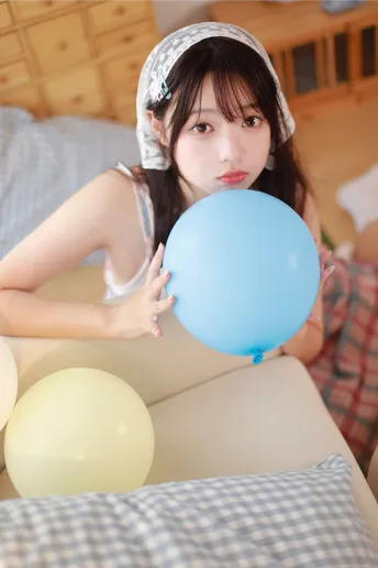 一位年轻女子站在床顶上拿着一个蓝色气球