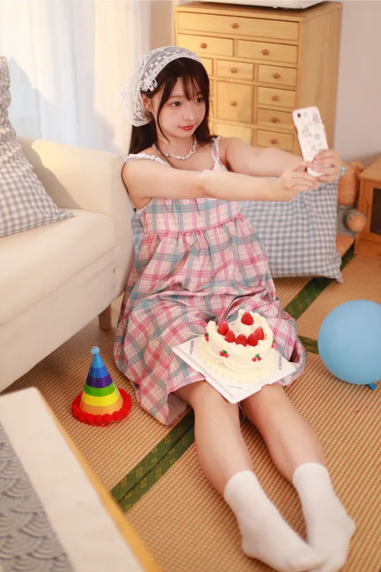 一个穿着连衣裙的年轻女子抱着一个小蛋糕坐在地板上