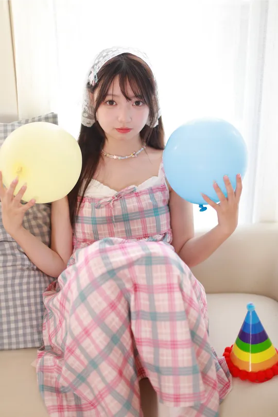 一个年轻女子坐在沙发上抱着一个球和一只蓝色气球。