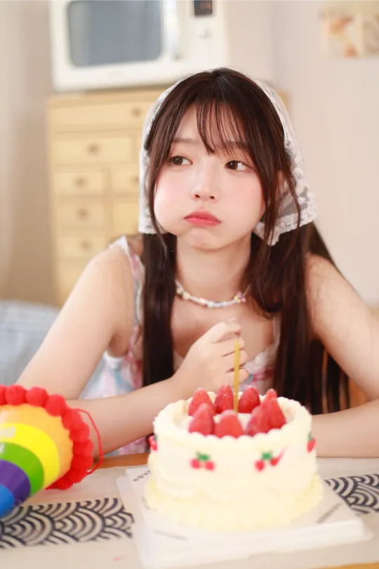 一个小女孩坐在桌子旁吹灭了她生日蛋糕上的蜡烛。