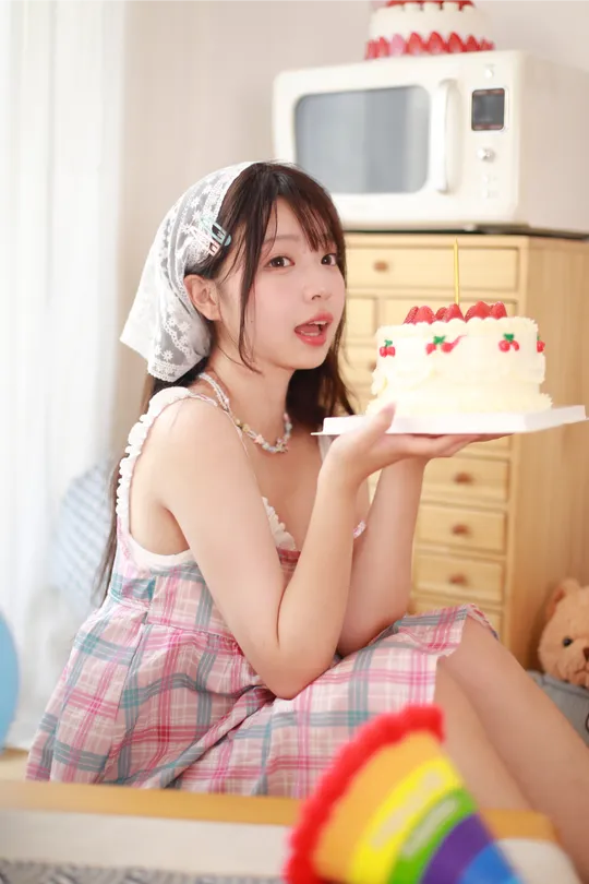 一个年轻女子端着一盘蛋糕坐在桌子旁