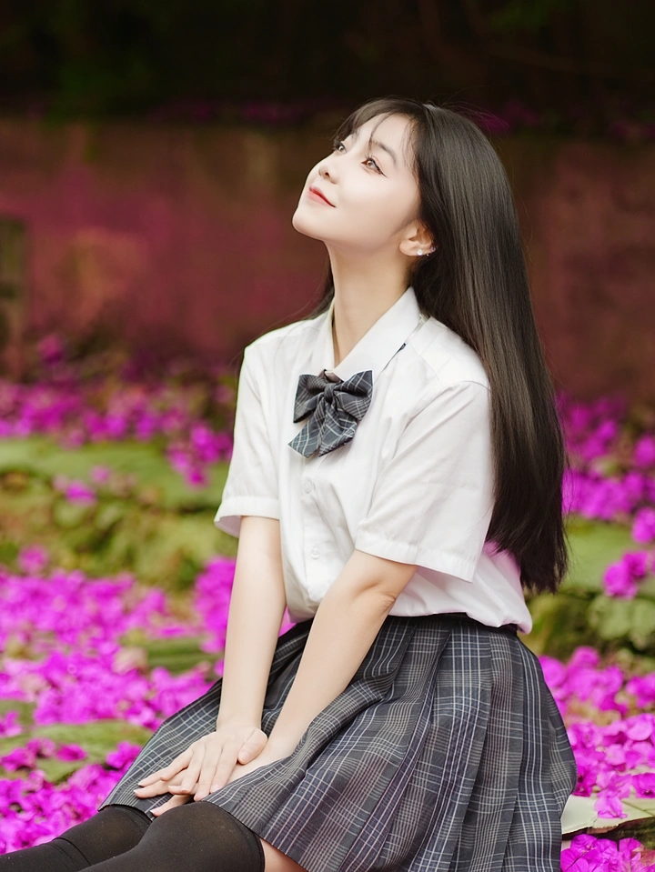 用镜头捕捉「青春与繁花」的对话，白衬衫、JK 格裙，搭配倾泻的紫花瀑，让少女与夏