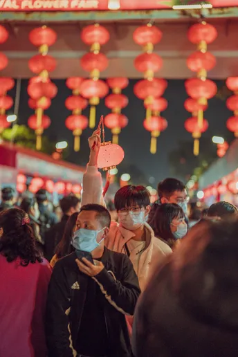 人们戴着口罩在挂着灯笼的街道上