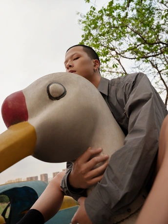 一个年轻人在操场的滑梯上抱着一个孩子的头