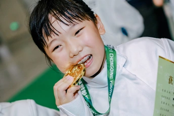 一个小男孩戴着金牌在脖子上吃东西 微笑着。