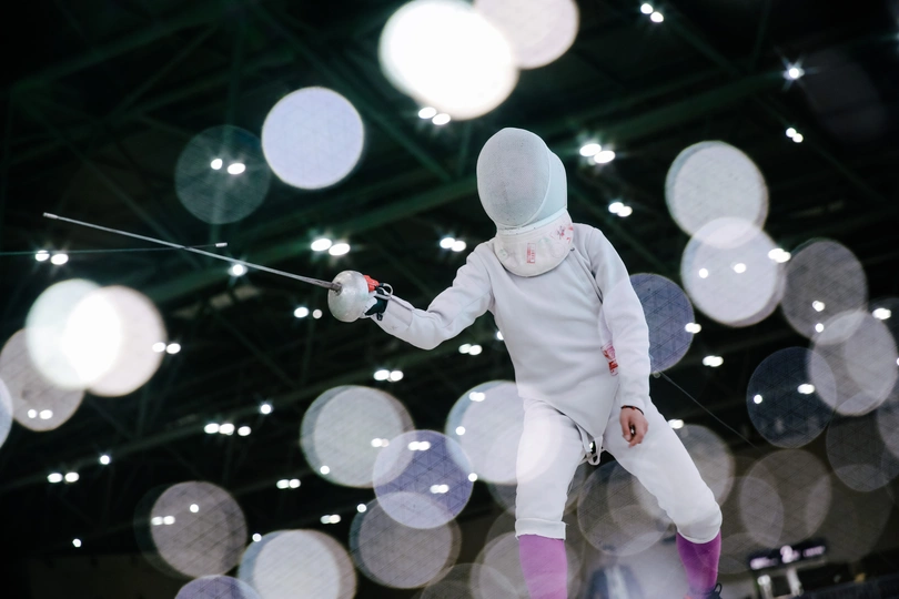 一个穿击剑服的男子站在一把剑旁边