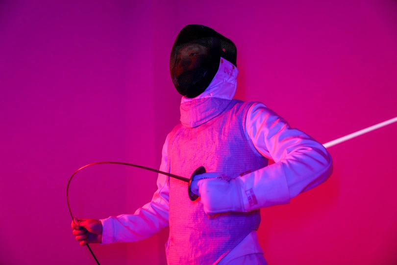 一个人穿着白色衣服拿着剑站在一个明亮照亮的墙上