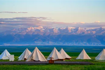 背景是山脉的草地上搭起了白色的帐篷。