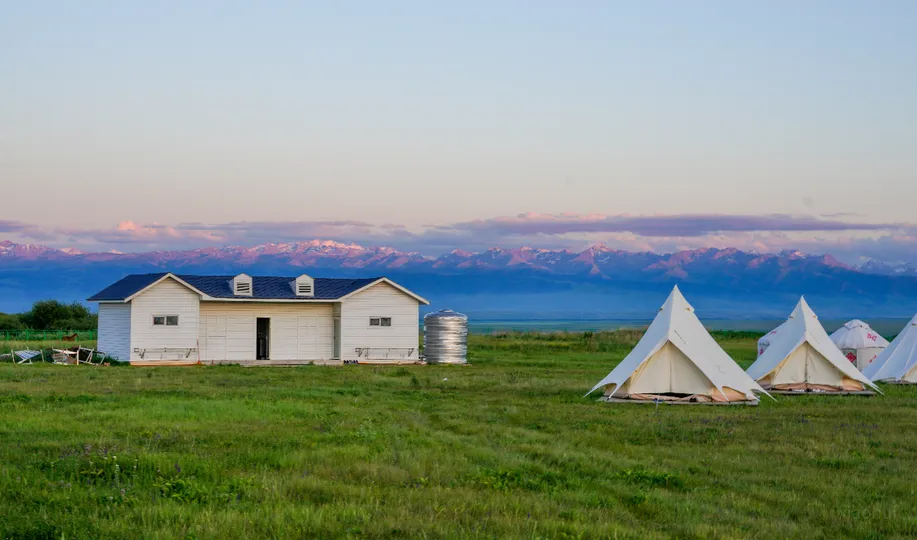 日落时的一片绿地上有一座白宫和帐篷