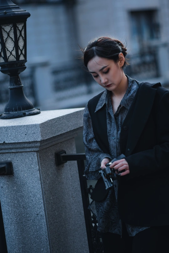 一位年轻女子靠在围栏上 正在看手机。