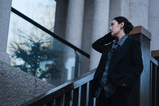 一个穿着黑色西装的年轻女子站在楼梯上 一个年轻男子走楼梯。