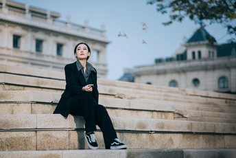 一个穿着全黑衣服的年轻女子坐在建筑物外的台阶上