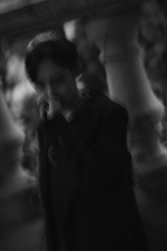 一张黑白照片 一个人在人们中间拿着一部智能手机的房间。