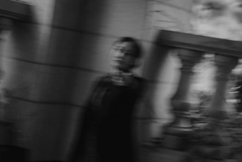 一张黑白照片 一位女士站在一栋建筑前