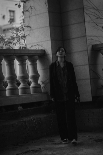 一位年轻女子走在一条街道上 旁边站着一名男子 他站在一栋建筑前。