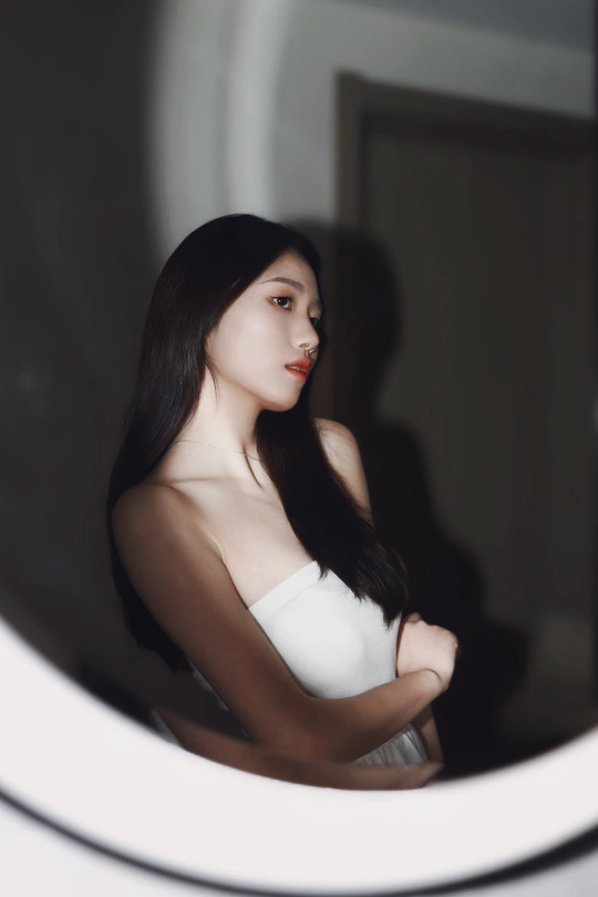 一位穿着白色连衣裙的年轻女子正在照镜子