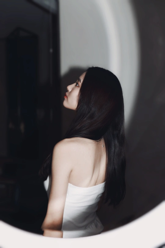 一位穿着白色连衣裙的年轻女子正在照镜子