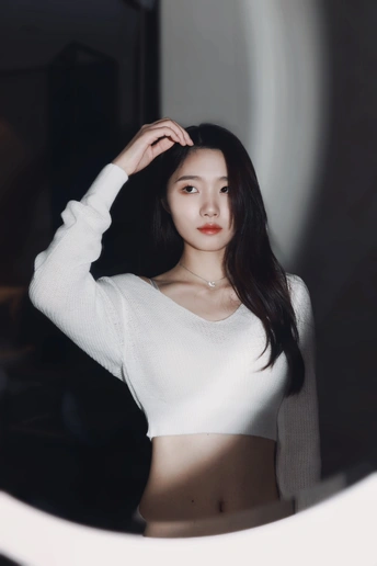 一位穿着白色毛衣的年轻女子站在镜子前