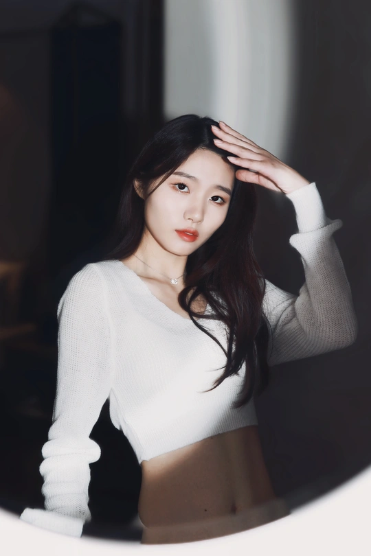 一位穿着白色毛衣的女士站在镜子前