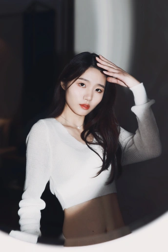 一位穿着白色毛衣的女士站在镜子前