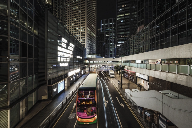 夜间行驶在城市中的双层公交车 周围有高楼大厦。