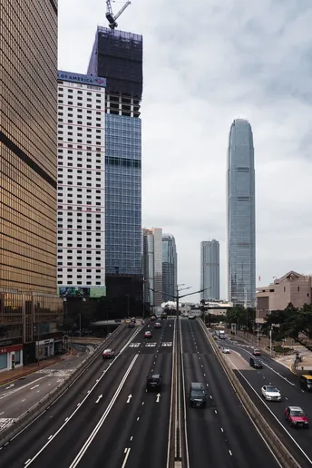 一些汽车在城市中行驶 周围有正在建造的高楼大厦。