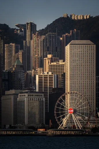 前方有大型铁力士游乐设施 周围有高楼大厦和一片水域。