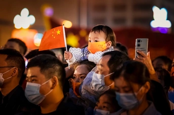 在人群中 一个戴着口罩的小孩坐在父亲的肩膀上挥舞着中国国旗