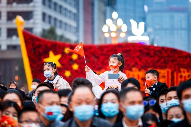 一群戴着口罩的人挥舞着中国国旗