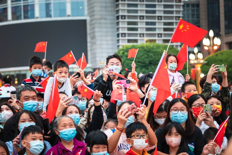 一群戴着口罩的人在抗议活动中挥舞国旗并拍照