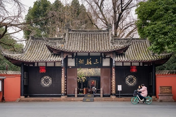 一位女士骑自行车经过一座小建筑