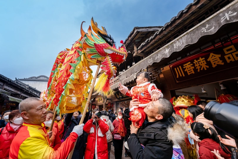 人们 carrying a red dragon through a festival