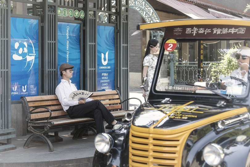 一个人坐在黄色公交车旁边的长凳上