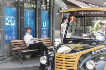 一个人坐在黄色公交车旁边的长凳上