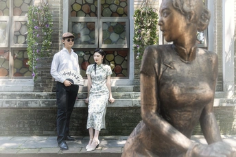 一个男人和一个女人在女人和男人站立在一尊雕塑的女性面前拍照。