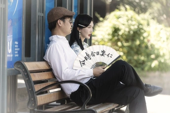 一个人和一个女人坐在公交车站的长凳上