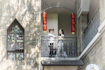 一位男子和一位女子站在一栋建筑物的阳台上 窗户上挂着中国灯笼。