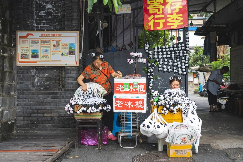一位妇女坐在街头摊贩前 售卖物品。