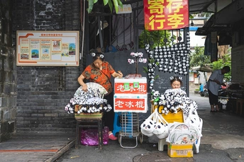 一位妇女坐在街头摊贩前 售卖物品。