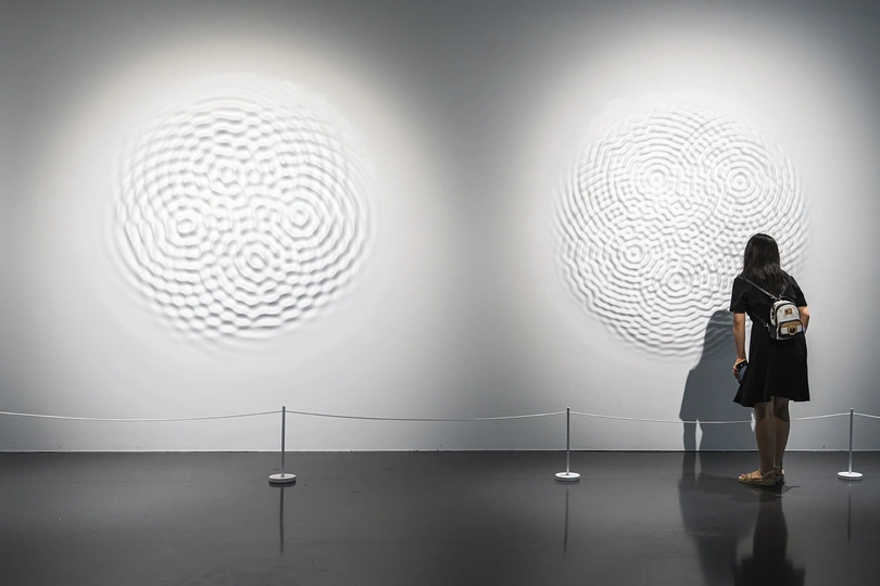 一个人站在博物馆或艺术画廊的白墙前的照片