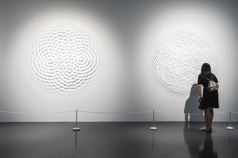 一个人站在博物馆或艺术画廊的白墙前的照片