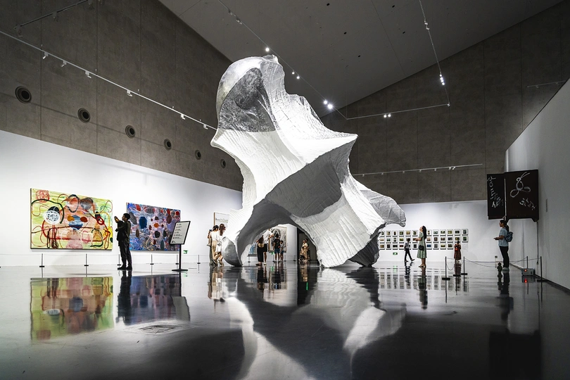 一群人穿过一个艺术画廊 墙上有一尊雕塑。