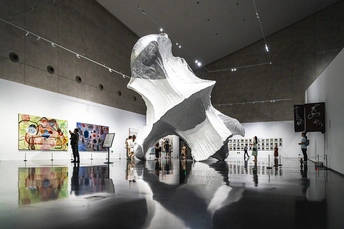 一群人穿过一个艺术画廊 墙上有一尊雕塑。